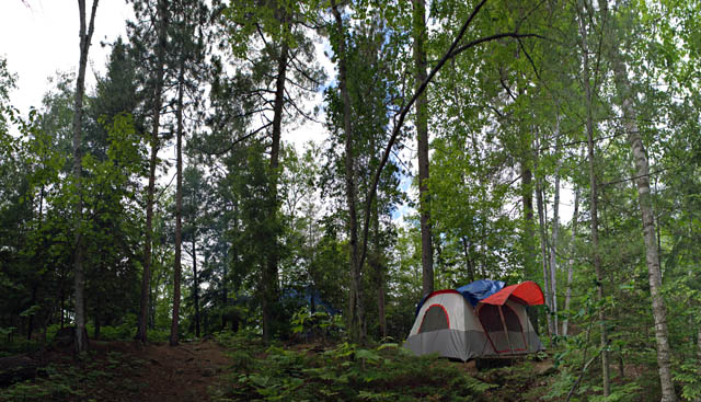 A wide angle panoramic view of a heavily wooded camp site in the Adirondacks.